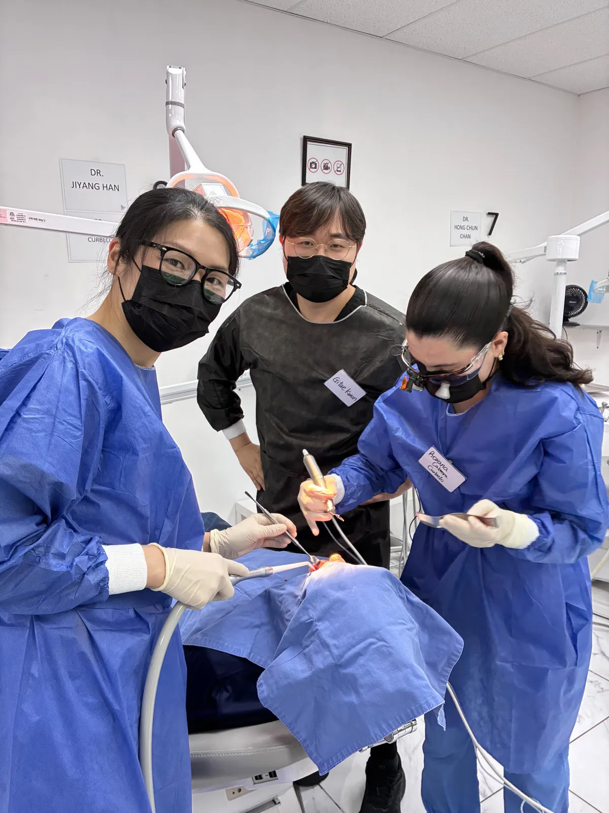 Dr. Kwon standing behind two dentists as they operate